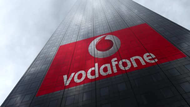 Vodafone logo på en skyskraber facade, der afspejler skyer, tid bortfalder. Redaktionel 3D-gengivelse – Stock-video