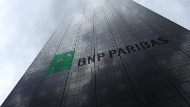 Логотип BNP Paribas на фасаде небоскреба, отражающий облака, время истекло. Редакционная 3D рендеринг — стоковое видео