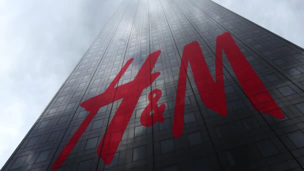 Логотип H M на фасаде небоскреба, отражающий облака, время истекло. Редакционная 3D рендеринг — стоковое видео