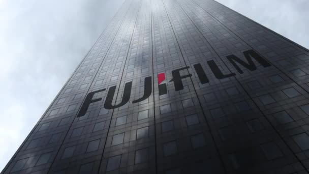 Логотип Fujifilm на фасаде небоскреба, отражающий облака, время истекло. Редакционная 3D рендеринг — стоковое видео