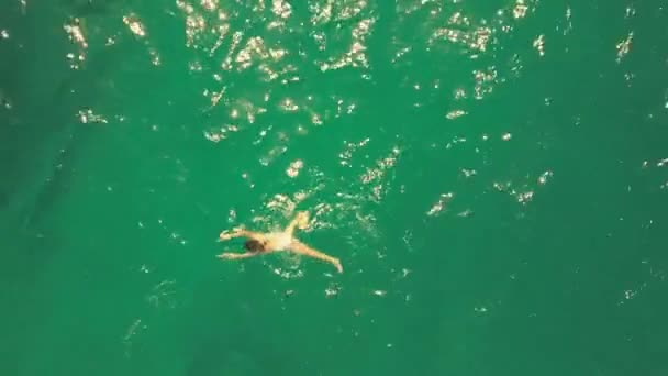 Aerial top down rising shot of a young woman swimming in the sea — Stock Video