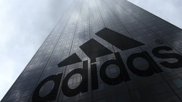 Prasasti Adidas dan logo pada fasad pencakar langit mencerminkan awan. Perenderan 3D Editorial — Stok Foto