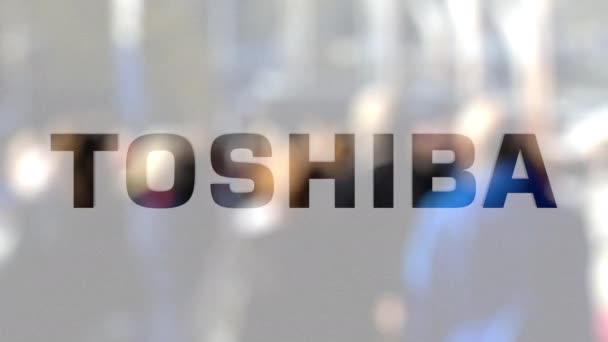 Toshiba Corporation logo na sklenici proti rozmazané dav na steet. Úvodník 3d vykreslování — Stock video