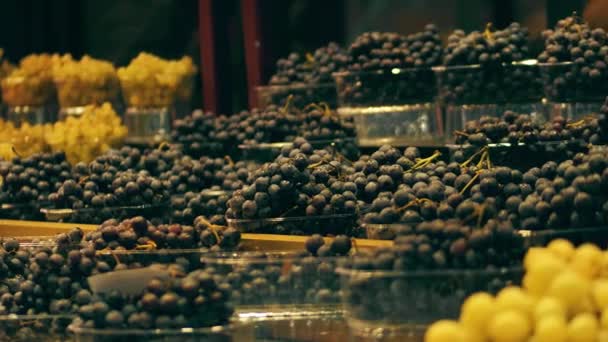 Vakken met wit en zwart druiven op fruit kraam op de markt — Stockvideo