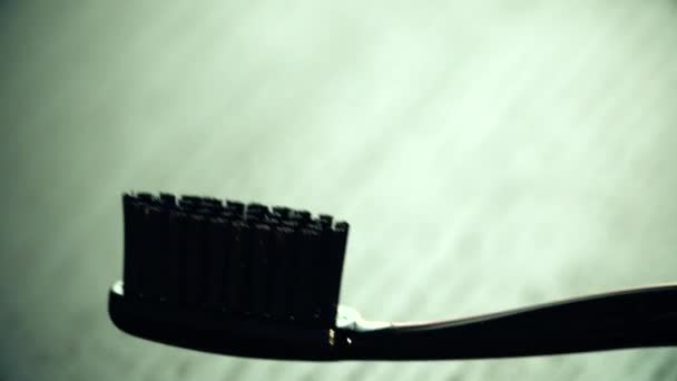 Tandpasta gelegd op de zwarte tandenborstel — Stockvideo
