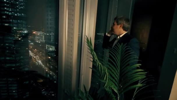 Ευτυχής επιχειρηματίας μιλάει στο κινητό του τηλέφωνο στο γραφείο στο κέντρο της πόλης το βράδυ — Αρχείο Βίντεο
