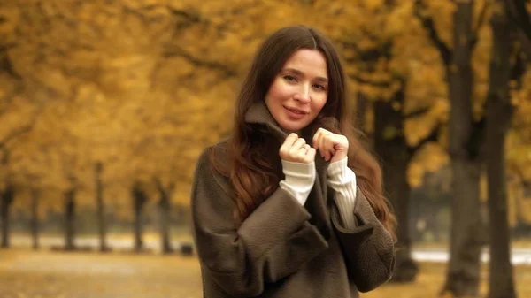 Όμορφη νεαρή μελαχρινή φοράει παλτό εξετάζει τη φωτογραφική μηχανή στο φθινόπωρο σοκάκι — Φωτογραφία Αρχείου