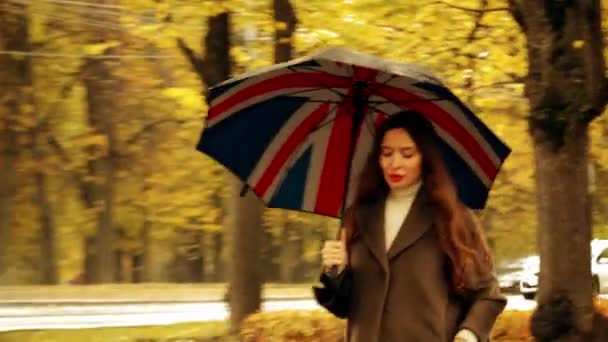 Όμορφη νεαρή γυναίκα το περπάτημα με ομπρέλα κατά μήκος φθινόπωρο δρομάκι σε μια βροχερή μέρα — Αρχείο Βίντεο
