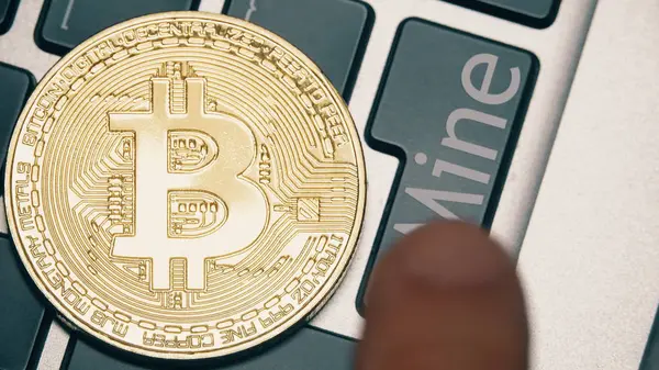 Shiny bitcoin on the computer keyboard and the Mine button being pressed — Stock Photo, Image