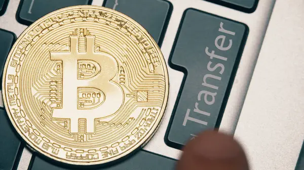Shiny bitcoin on the computer keyboard and the Transfer button being pressed — Stock Photo, Image