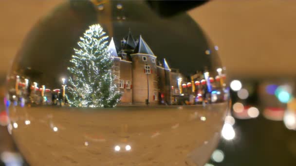 Velké zdobené vánoční strom v večer, zobrazit přes skleněnou kouli. Amsterdam, Nizozemsko — Stock video