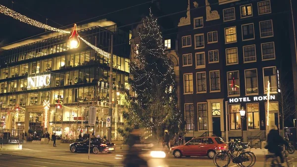 AMSTERDAM, PAÍSES BAJOS - 28 DE DICIEMBRE DE 2017. Gran árbol de Navidad decorado y tráfico nocturno en la calle principal de Rokin — Foto de Stock