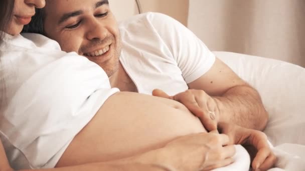 男子抚摸怀孕妻子腹部在床上在家 — 图库视频影像