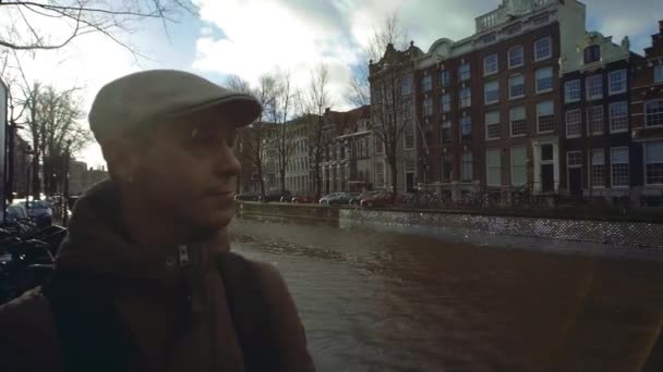 Молодой человек прогуливается по городскому каналу в Амстердаме, Нидерланды — стоковое видео