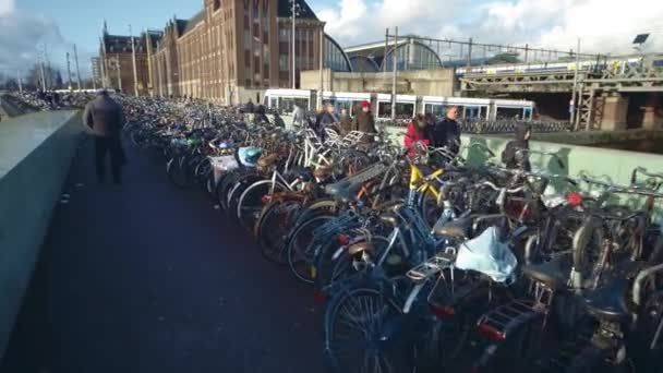 AMSTERDAM, PAÍSES BAJOS - 26 DE DICIEMBRE DE 2017. Gran aparcamiento de bicicletas y tranvía en movimiento y tren en la ciudad — Vídeos de Stock