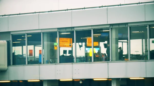 Onbekende passagiers in de vertreklounge van de internationale luchthaven van Chopin, uitzicht vanaf buiten. Warsaw, Polen — Stockfoto