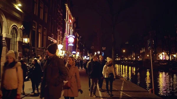 Amsterdam, Nizozemsko - 27 prosinec 2017. Procházka podél nábřeží kanálu přeplněném městě večer — Stock fotografie