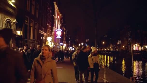 AMSTERDAM, PAÍSES BAJOS - 27 DE DICIEMBRE DE 2017. POV caminar a lo largo de la ciudad abarrotada terraplén del canal por la noche — Vídeos de Stock