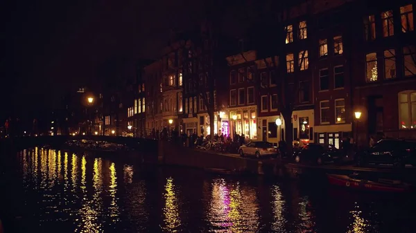 Amsterdam, Nederländerna - 27 December 2017. Trångt staden kanalen vallen och bro på natten — Stockfoto