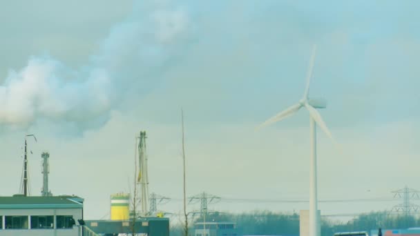 Rotující větrné elektrárny a kouř nad průmyslové zóny. Čisté a špinavé energetické koncepce výroby — Stock video