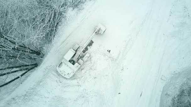 Vista aérea de arriba hacia abajo de una excavadora de orugas en la nieve — Vídeos de Stock