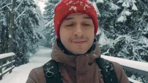 Giovane uomo escursioni lungo la strada forestale invernale in neve caduta — Video Stock