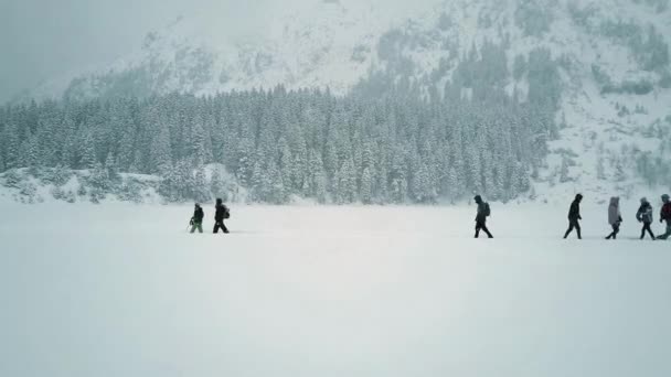 Luftaufnahme aus niedriger Höhe von unkenntlich gemachten Personen beim Wandern auf dem verschneiten See — Stockvideo