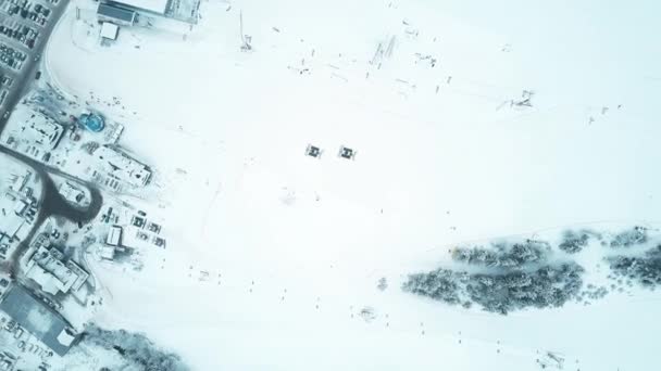 Vista aerea dall'alto verso il basso di due gatti delle nevi o raccoglitori di neve su una pista da sci di montagna — Video Stock