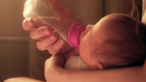여자 신생아 아기 병 젖꼭지에서 그녀의 엄마 손에 음료 — 비디오