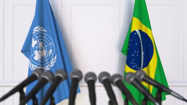 Flagi Organizacji Narodów Zjednoczonych i Brazylii na międzynarodowej konferencji prasowej spotkania lub negocjacji — Wideo stockowe
