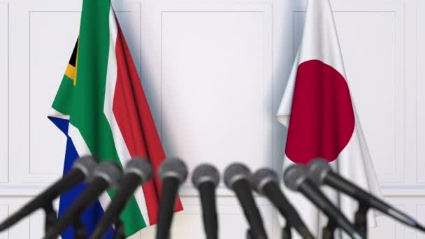 Flags of South Africa and Japan at international meeting or negotiations press conference — Stock Video