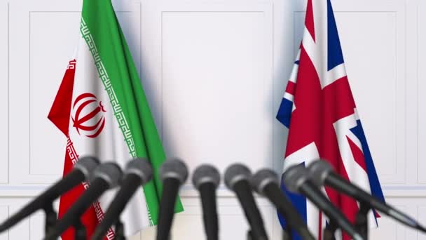 Флаги Ирана и Великобритании на международной встрече или пресс-конференции — стоковое видео