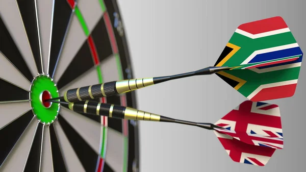 Flags of South Africa and the United Kingdom on darts hitting bullseye of the target. International cooperation or competition conceptual 3D rendering — Stock Photo, Image