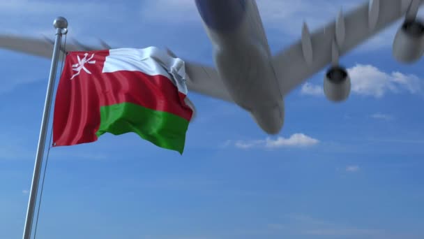 Commercial airplane flying above waving flag of Oman. Omani emigration or tourism related animation — Stock Video