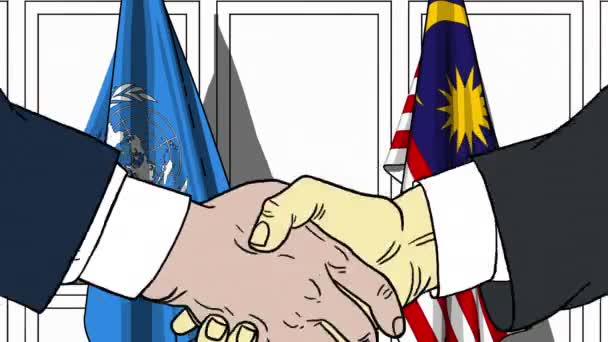 Επιχειρηματίες ή πολιτικοί χειραψία κατά σημαίες των Ηνωμένων Εθνών και τη Μαλαισία. Επίσημη συνάντηση ή συνεργασίας που σχετίζονται με εκδοτική κίνηση — Αρχείο Βίντεο