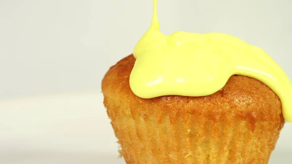 Pouring yellow glaze on cupcake, macro shot — 스톡 사진