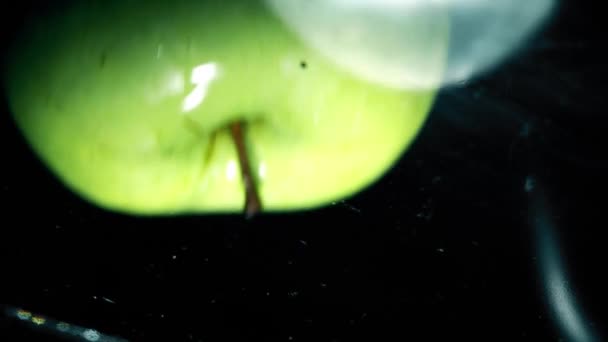 Green apple falls into water in a glass pan, view from below. Slow motion close-up shot — 图库视频影像