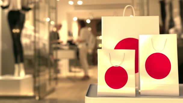 Bulanık mağazaya karşı Japon bayrağı taşıyan alışveriş torbaları. Japon alışveriş videosu — Stok video