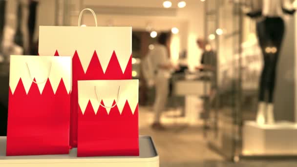 Papperspåsar med Bahrains flagga mot suddig butik. Bahrains shoppingrelaterade klipp — Stockvideo