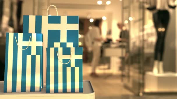 Τσάντες αγορών με τη σημαία της Ελλάδας ενάντια στο θολή κατάστημα. Ελληνικό κλιπ σχετικό με ψώνια — Αρχείο Βίντεο