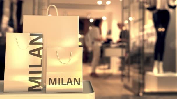 Paper shopping bags with MILAN text against blurred store. Italian shopping related clip — Stock video