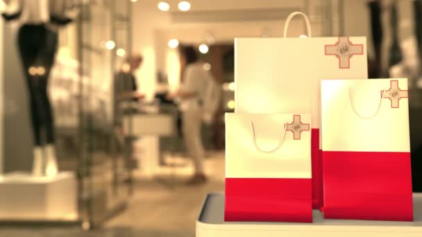 Bulanık mağaza girişine karşı kağıt alışveriş torbalarının üzerinde Malta bayrağı. Perakende ile ilgili klip — Stok video