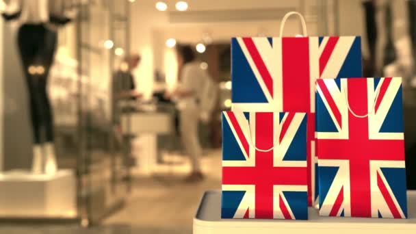 英国のフラグは、紙のショッピングバッグにぼやけた店の入り口に対して。小売関連クリップ — ストック動画