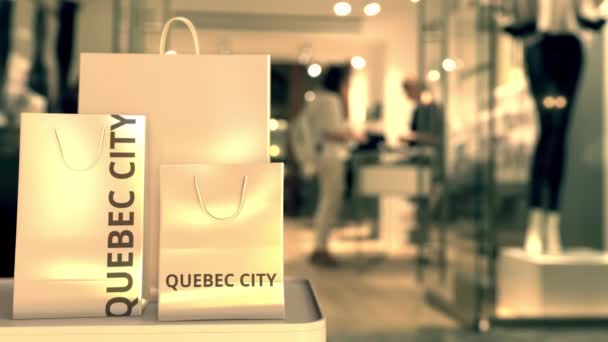 Paper shopping bags with QUEBEC CITY text against blurred store. Canadian shopping related clip — Stock Video