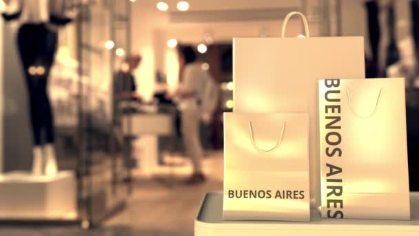 Bolsas de compras de papel con texto BUENOS AIRES contra tienda borrosa. Español compras relacionadas clip — Vídeo de stock