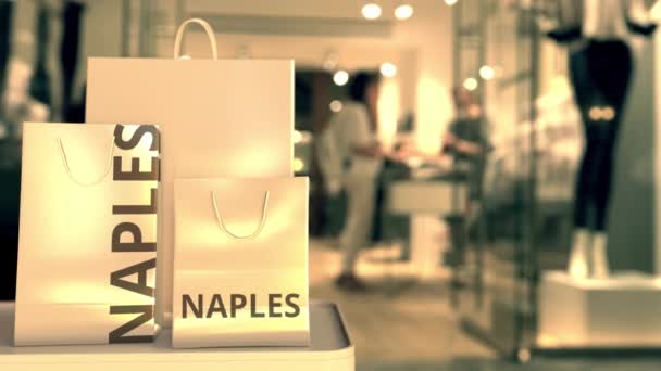 Paper shopping bags with NAPLES text against blurred store. Italian shopping related clip — Stock Video