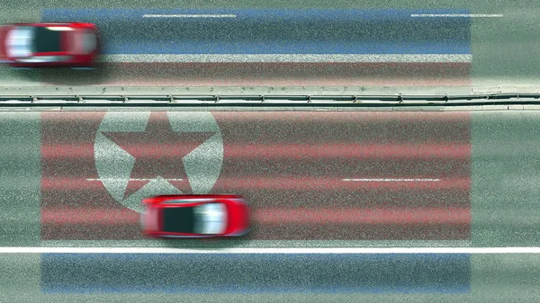 Vista aerea dall'alto verso il basso di automobili e bandiera della Corea del Nord sulla strada. Rendering 3D concettuale in viaggio — Foto Stock