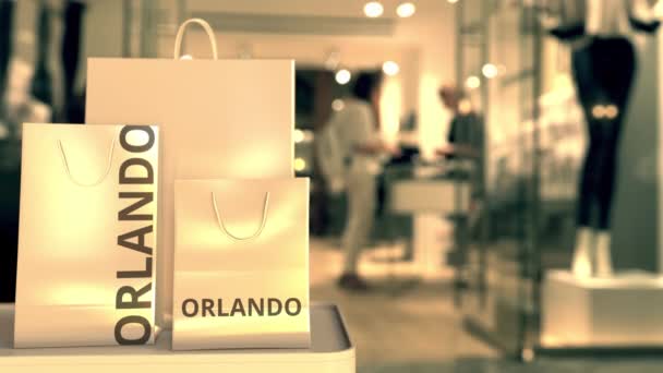 Papiereinkaufstüten mit orlando-farbener Bildunterschrift vor verschwommenem Ladeneingang. Einzelhandel in den Vereinigten Staaten im Zusammenhang mit 3D-Animation — Stockvideo