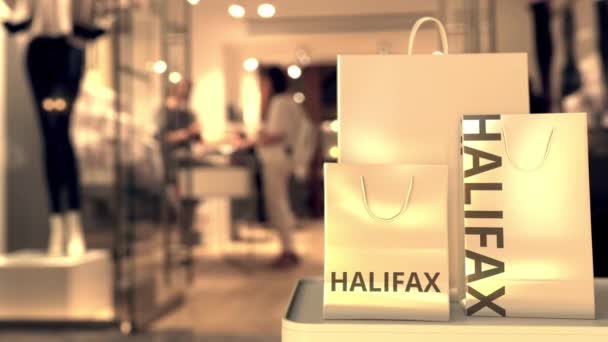 ぼやけた店の入り口に対するハリファックスキャプション付きのショッピングバッグ。カナダでのショッピング関連の概念3Dアニメーション — ストック動画