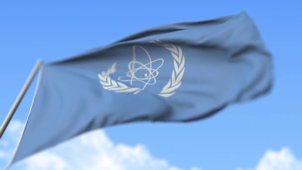 Viftande flagga Internationella atomenergiorganet Iaea, låg vinkel vy. Redaktionell loopable realistisk slow motion 3D-animation — Stockvideo